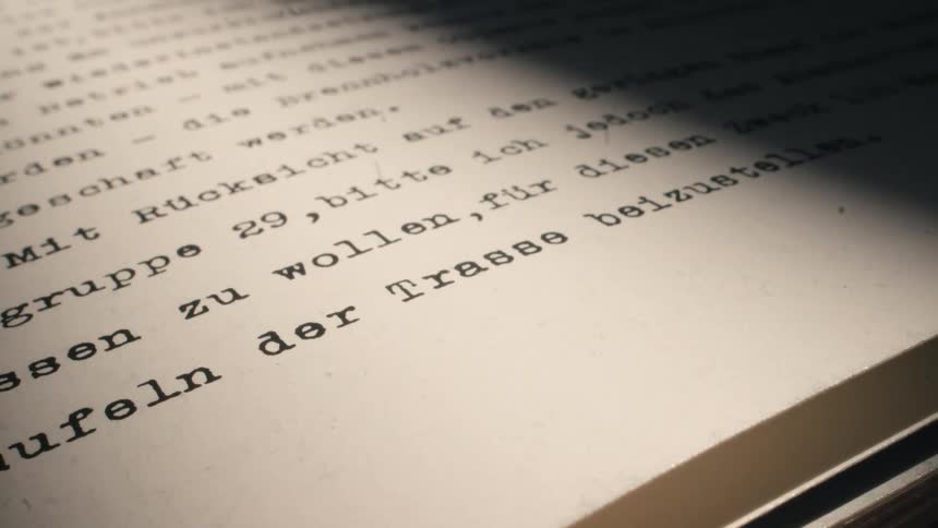 A close-up of a vintage German typed document with a mysterious light moving across the page