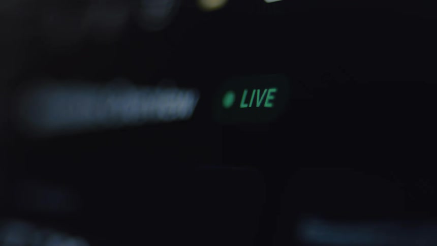 A close-up macro shot of a green 'LIVE' streaming indicator glowing on a dark digital screen