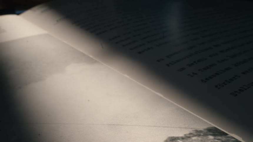 Close-up of a vintage German document with typewriter text, illuminated by a moving light creating dramatic shadows