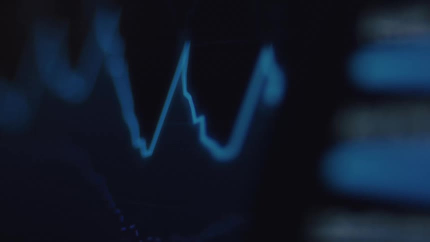 A macro close-up of a blue digital stock market or cryptocurrency chart on a screen showing real-time price volatility and fluctuations
