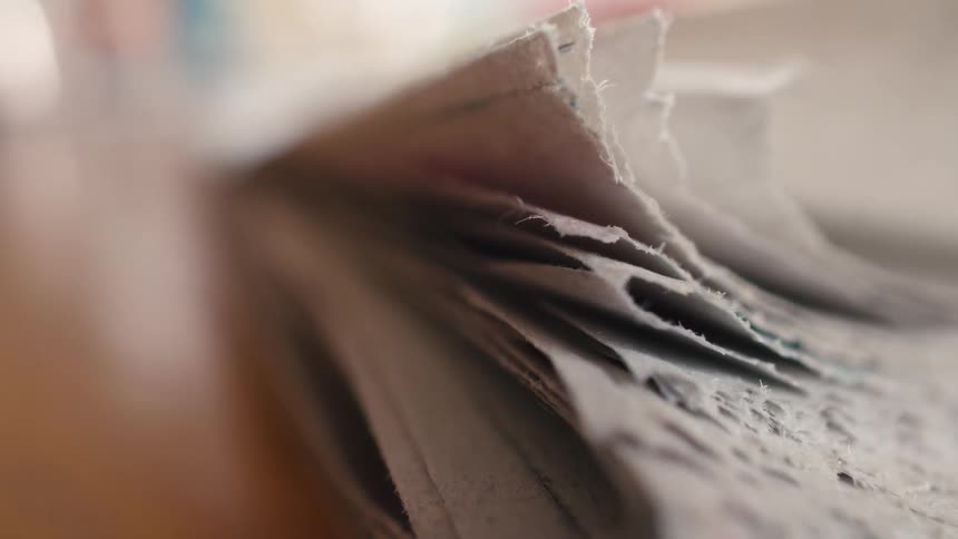 Close up of a pile of newspapers laying on a wooden table with soft focus