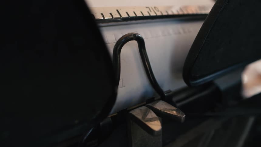 Extreme close-up of the mechanical hammers of an old typewriter imprinting letters onto a page