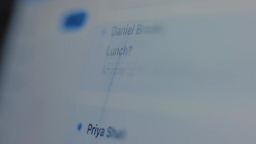 A close-up, out-of-focus shot of an email inbox with messages continuously scrolling on a computer screen