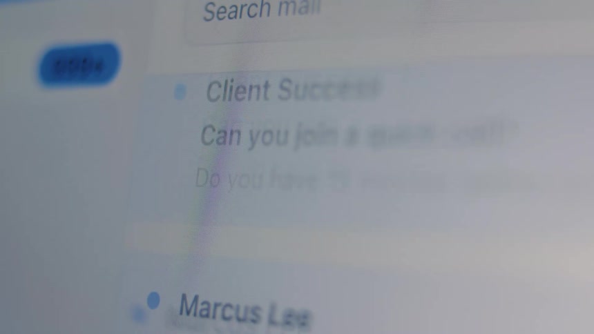 A close-up shot of a person scrolling through a busy work email inbox on a computer screen