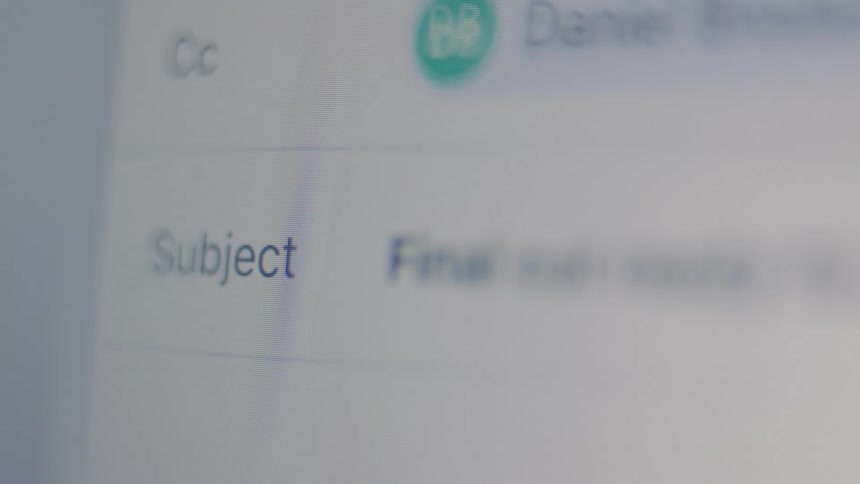 Close-up shot of a person typing the subject line and beginning to write the body of an email on a computer screen