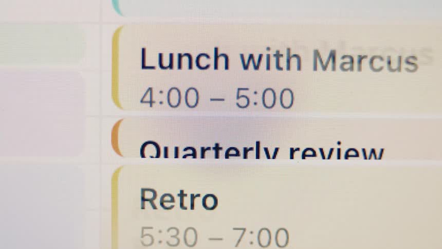 A close-up view of a digital calendar displaying a busy work schedule with meetings like 'Quarterly review' and 'Lunch with Marcus'