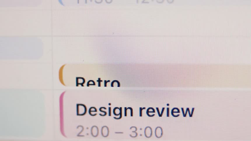 A close-up of a digital calendar on a screen displaying a schedule of work meetings and appointments