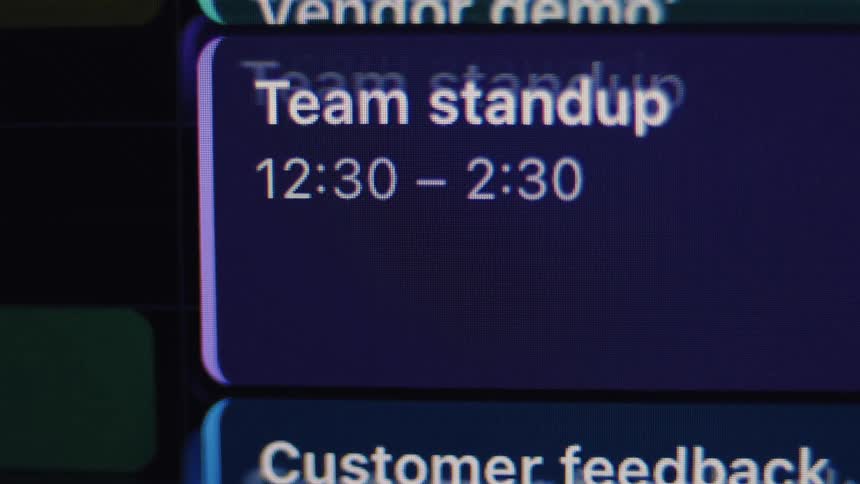 An extreme close-up shot of a digital project management board showing a scheduled 'Team Standup' meeting