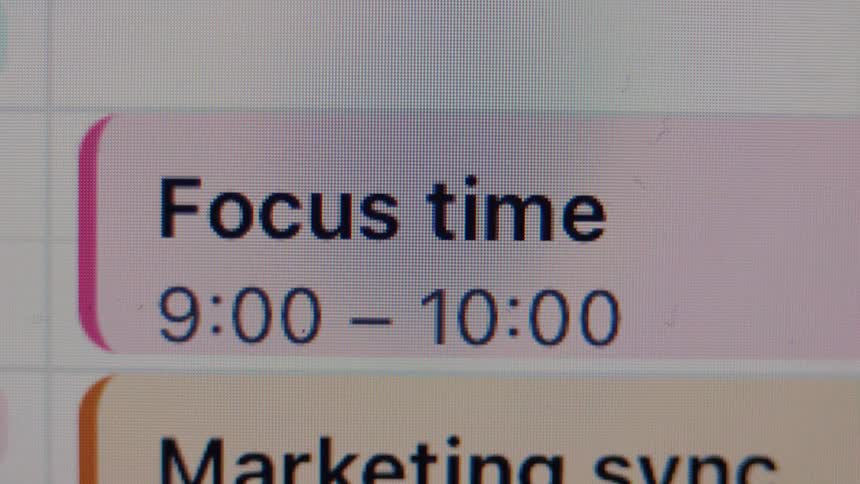 A macro shot of a digital calendar scrolls through daily appointments, highlighting a block for 'Focus time' from 9 to 10 AM