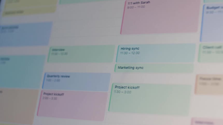A close-up panning shot reveals a busy digital calendar filled with color-coded meetings and appointments