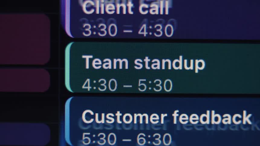 Extreme close-up of a digital calendar showing a busy work schedule being filled with meetings