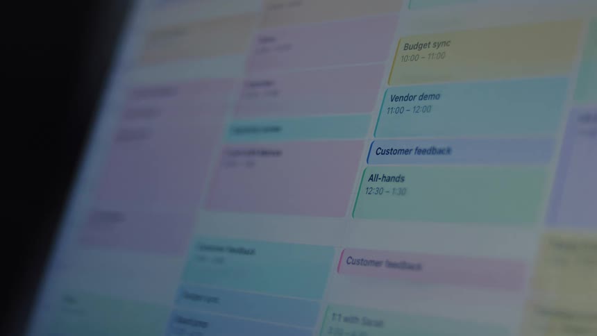A close-up shot of a digital work calendar on a computer screen being filled with meetings and appointments