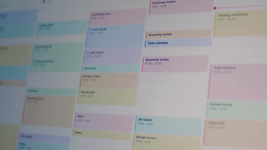 A close-up shot of a digital work calendar being filled with various color-coded meetings and events