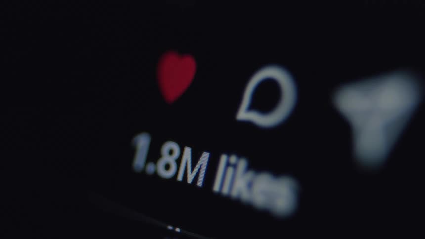 An extreme close-up of a social media post's like counter rapidly increasing on a dark screen