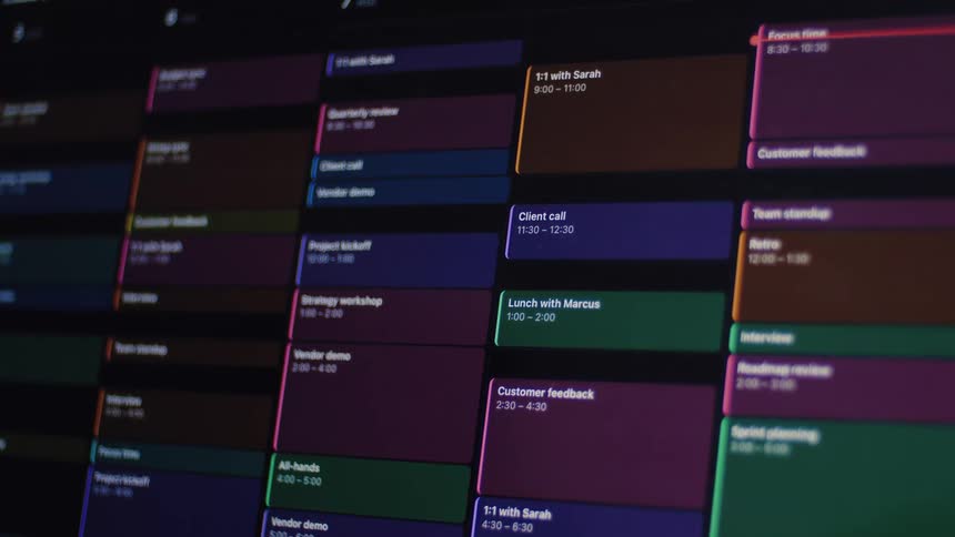 A close-up view of a digital calendar slowly zooming out to reveal a fully packed work schedule with colorful blocks