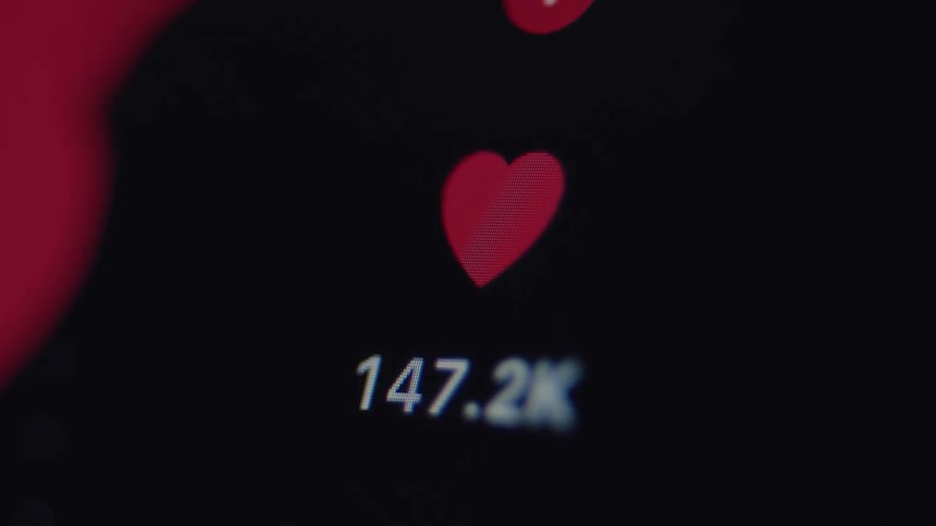 Macro shot of a social media 'like' counter rapidly increasing as a post goes viral, showing a red heart icon and rising numbers
