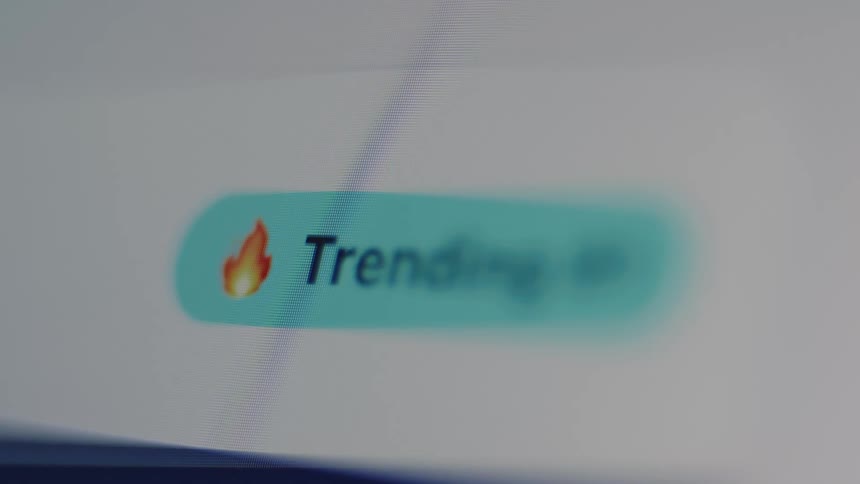 Extreme close up on a 'Trending' button with a fire emoji on a digital screen
