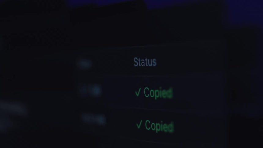 A close-up of a computer screen showing a successful data transfer with a green "Copied" status message in a dark room