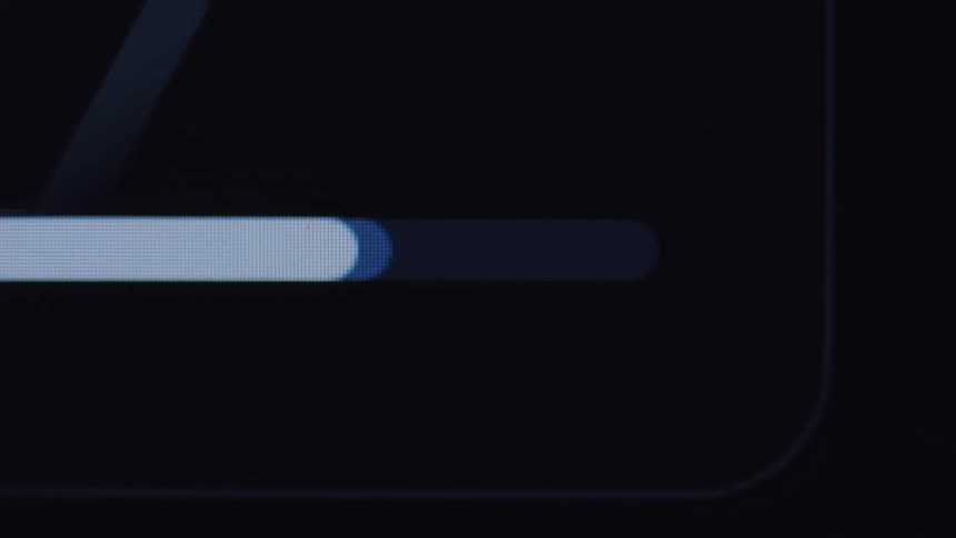 A close-up, macro view shows a digital loading bar filling up on a dark screen, indicating a completed process