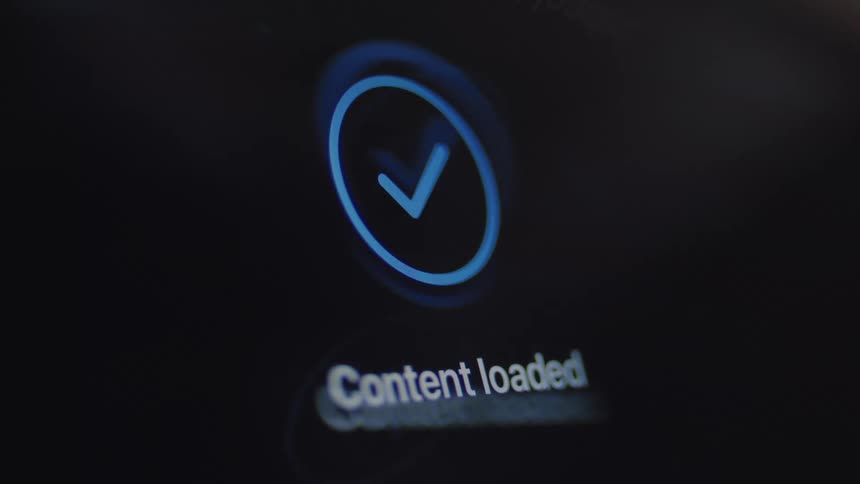 A close-up of a loading animation on a digital screen shows a circular progress bar completing and displaying a checkmark to indicate the content is loaded