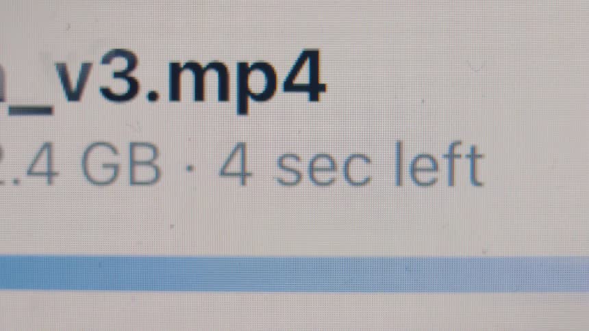 Close-up macro shot of a computer screen showing a large MP4 video file download with a progress bar and a time remaining countdown