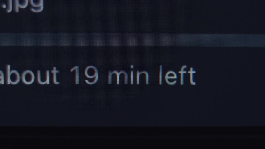 Extreme close-up on a computer screen displaying an unstable time remaining countdown for a file transfer