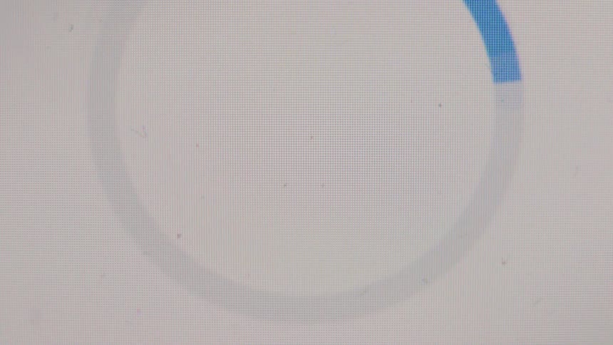 A close-up macro shot of a blue loading icon on a digital screen completing its animation and turning into a success checkmark