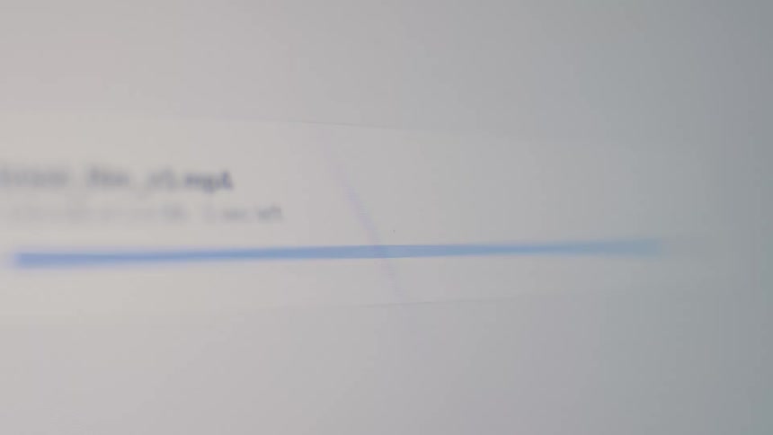 Close-up of a digital file upload progress bar finishing on a computer screen, ending with a success checkmark
