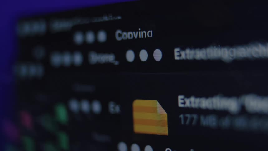 An angled macro shot of a computer screen shows the process of copying and extracting large data files in a dark room