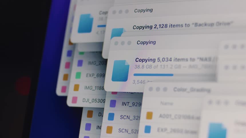 A close-up shot of multiple file copying progress windows stacked on a computer monitor