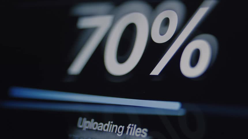 Close-up of a digital screen showing a file upload progress bar counting up to one hundred percent, ending with a completed checkmark icon