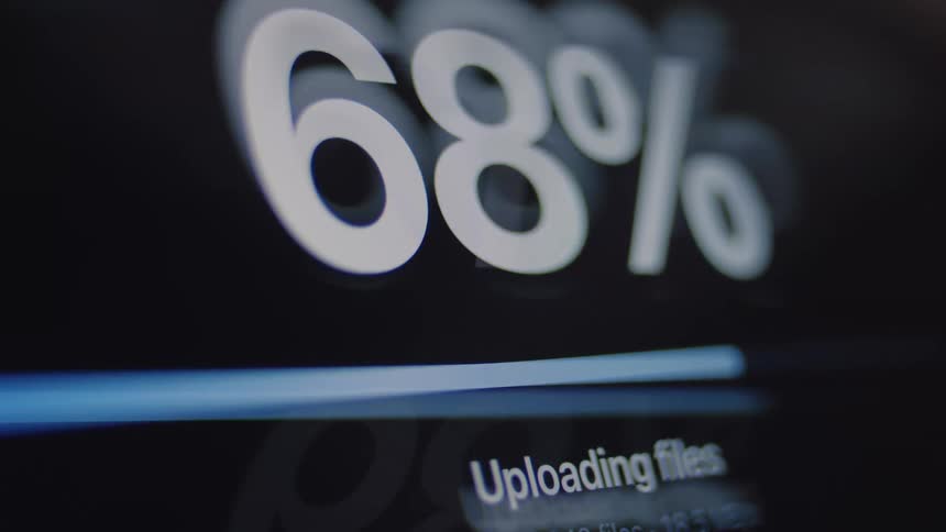 A close-up of a digital screen shows a file upload process with a progress bar and percentage count reaching completion