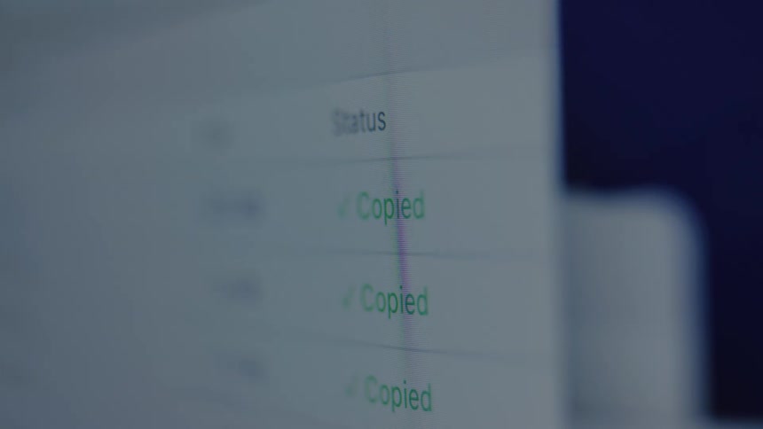A close-up view of a computer screen shows a blinking green 'Copied' status, indicating a successful data transfer