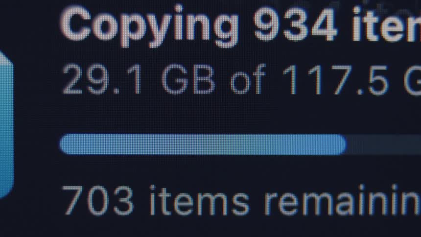 A close-up of a computer screen shows the progress bar as large files are being copied or transferred