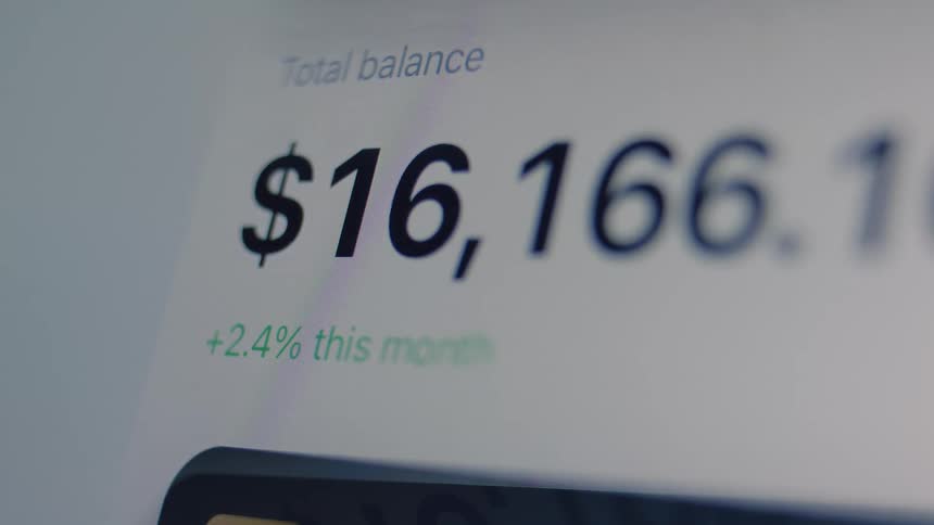 A close-up of a digital screen showing an investment portfolio's total balance decreasing in real-time