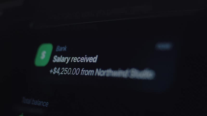 A close-up shot of a smartphone screen showing a 'Salary received' notification on a dark mode financial application