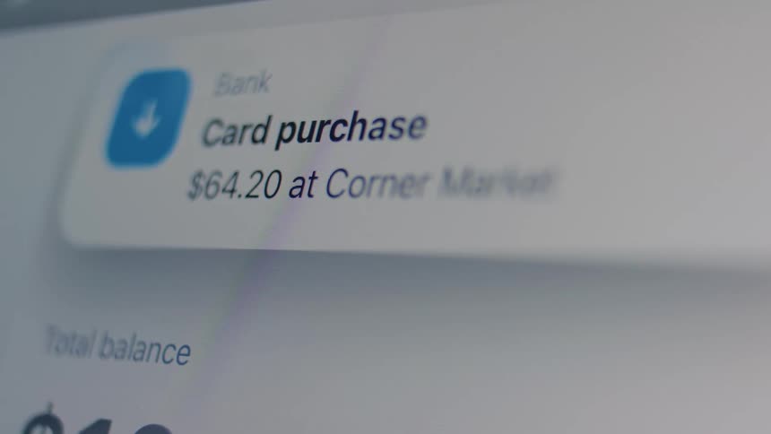 A macro shot of a digital banking app screen displays a pop-up notification for a recent card purchase