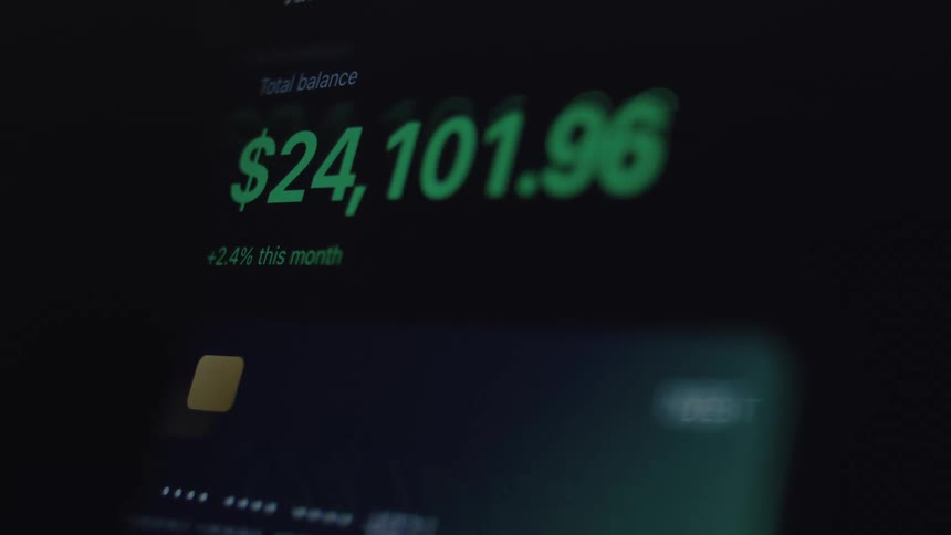 A close-up of a digital screen shows a bank account balance rapidly increasing, symbolizing financial growth and successful investments