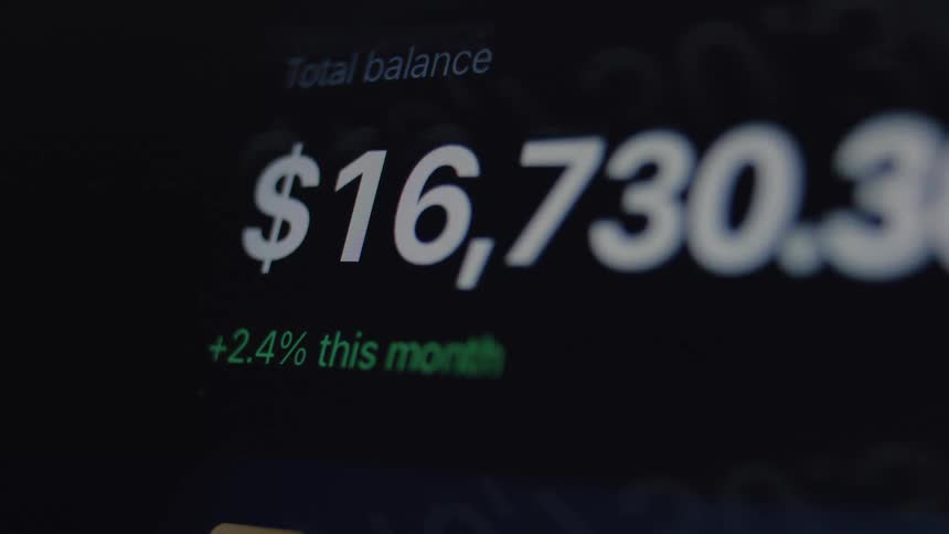 A close-up of a digital financial account where the total balance flashes red, indicating volatility or a warning