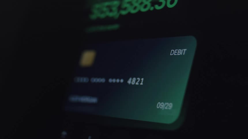 Close-up of a digital debit card on a screen showing a bank account balance rapidly increasing