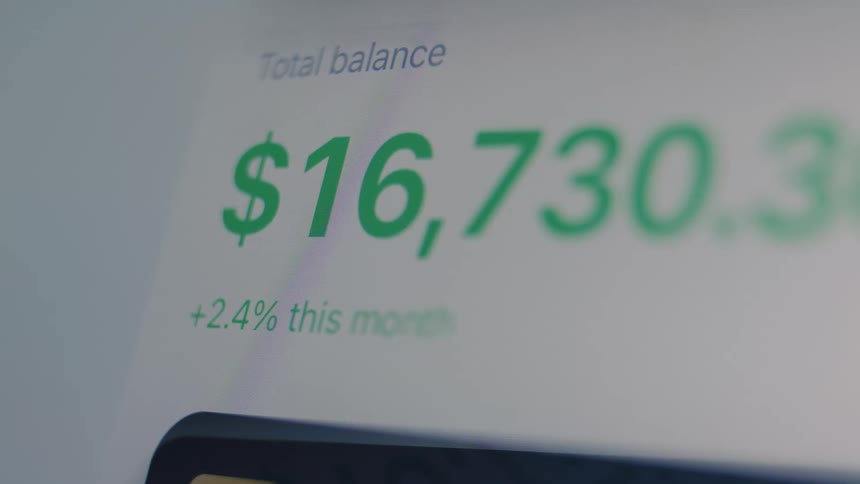A close-up of a digital display shows a bank account's total balance rapidly increasing, symbolizing financial growth and success
