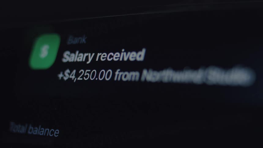 A close-up shot of a digital banking app notification on a dark screen showing a salary has been received