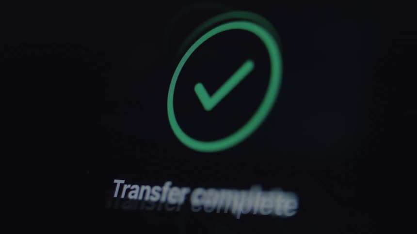 A successful digital transaction is confirmed with a loading circle turning into a green checkmark on a dark screen