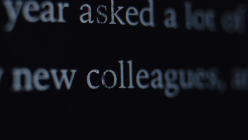 A macro close-up of a person typing the words 'new colleagues' on a dark computer screen