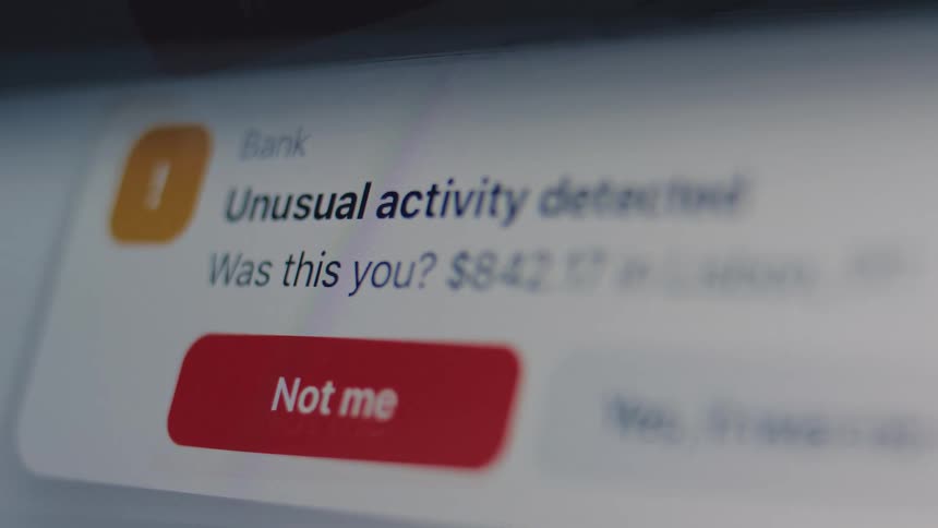 A macro view of a banking app notification on a digital screen alerting the user to unusual activity and potential fraud