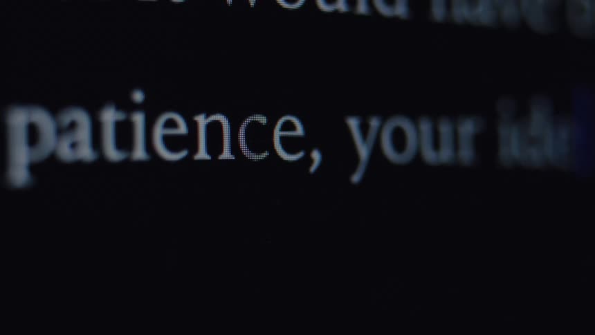 An extreme close-up of the word 'patience' being typed on a black computer screen