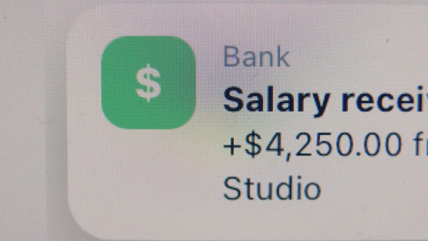 A macro shot shows a banking app notification on a digital screen for a salary of $4,250 being received
