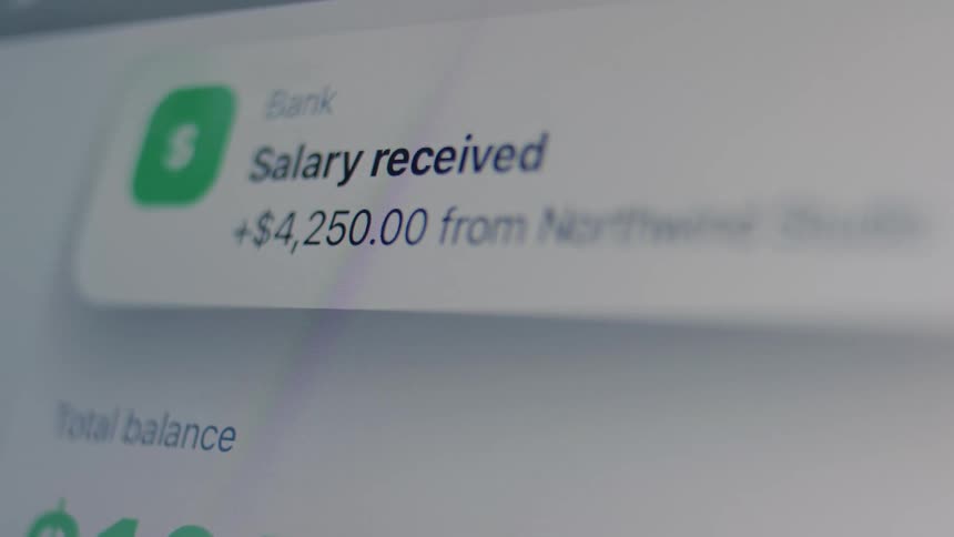 A close-up of a digital banking app on a screen showing a notification for a salary payment being received