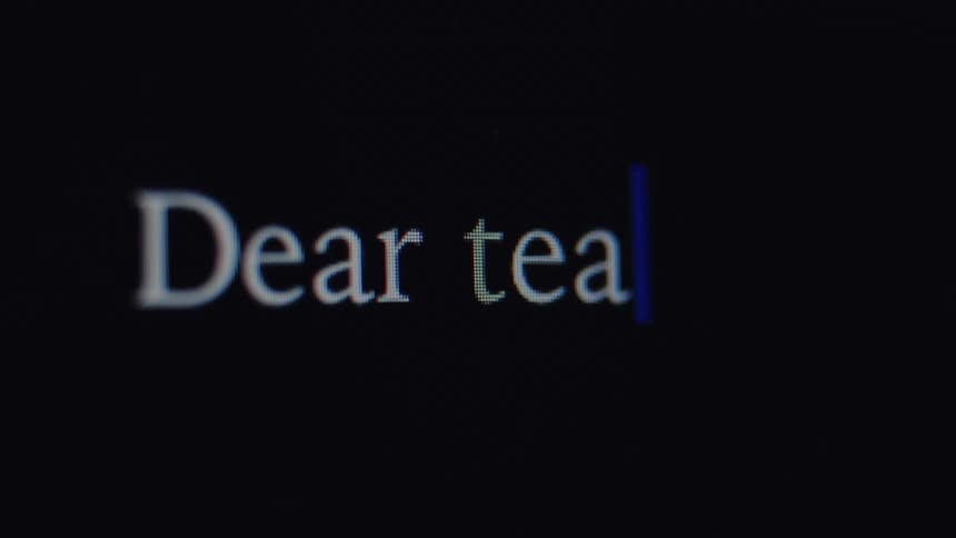 A close-up of someone typing the words 'Dear team,' on a computer screen
