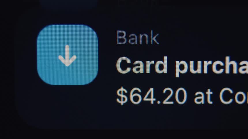 An extreme macro shot of a digital screen reveals glitchy, scrolling notifications of a bank card purchase